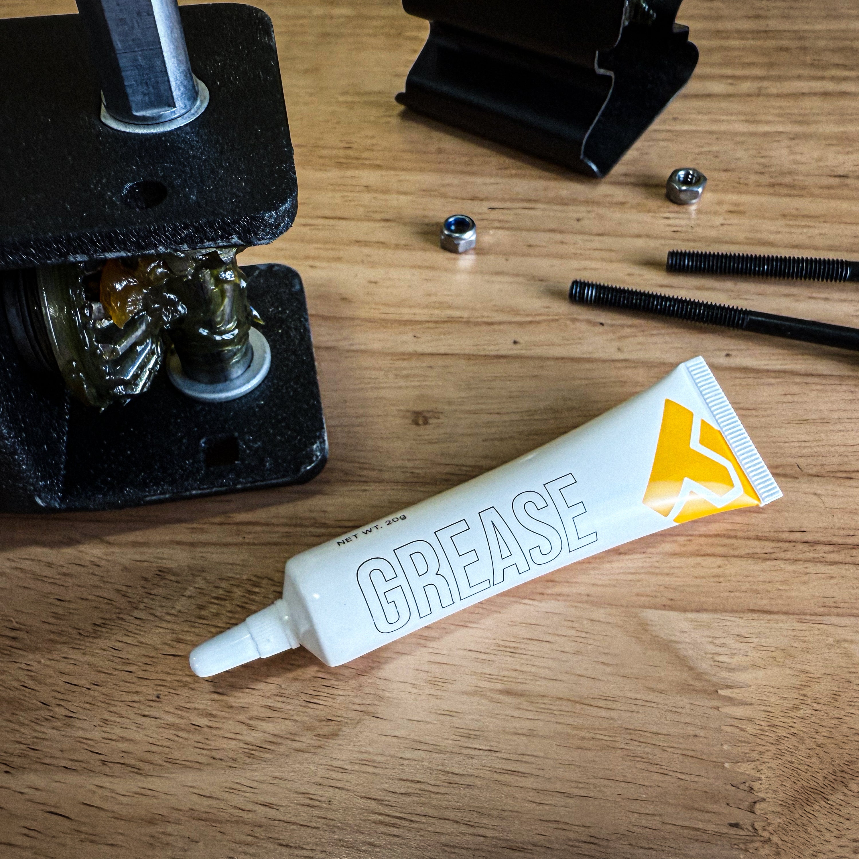 Tube of Trailer Valet grease next to gear assembly and mounting hardware for trailer dolly maintenance and lubrication