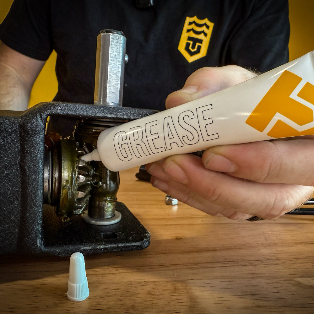 Applying Trailer Valet grease to internal gear assembly on trailer dolly for routine maintenance and performance